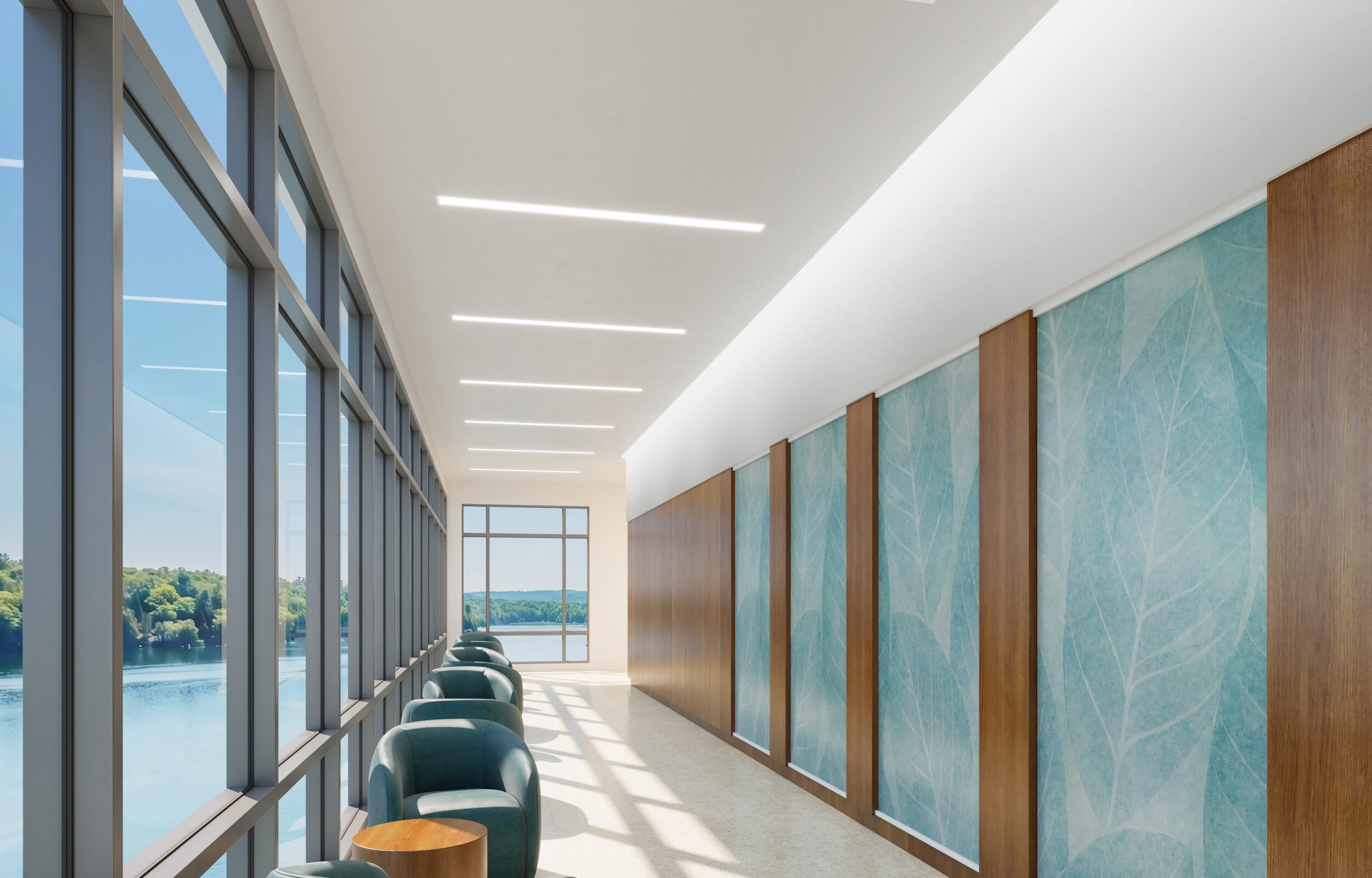 A bright healthcare corridor with floor-to-ceiling windows overlooking water, lit by recessed Focal Point Seem 4 Behavioral Health linear luminaires in the ceiling