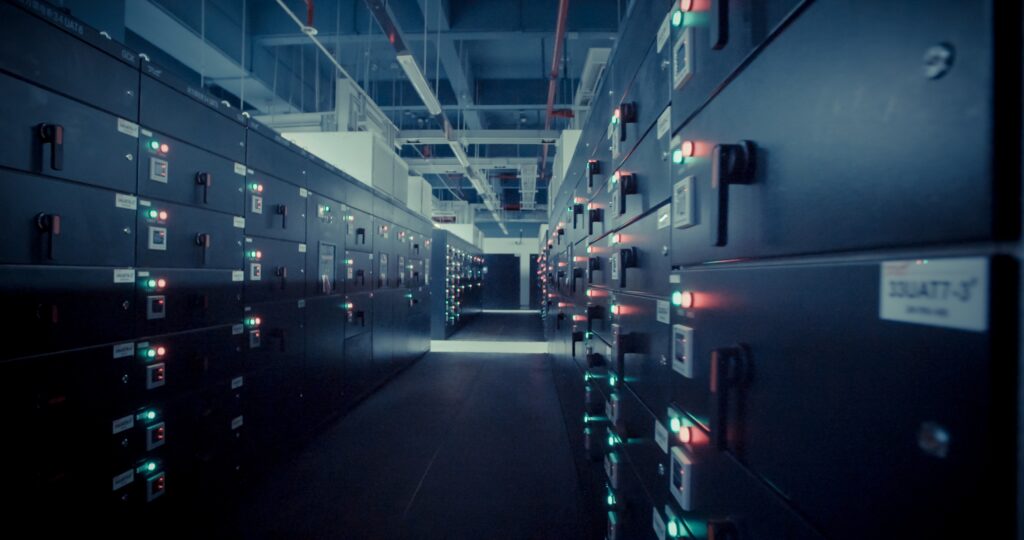 Dimly lit data center aisle lined with server racks and blinking status lights